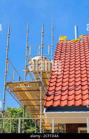 New roof tiles on house with scaffolding and blue sky Stock Photo