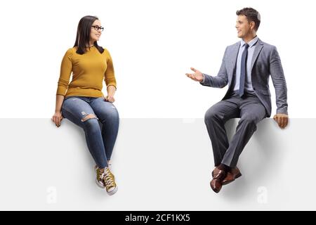 Young woman with glasses sitting on a blank panel and talking to a man in a suit isolated on white background Stock Photo