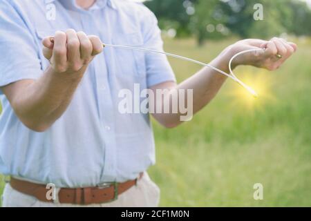 Man dowsing wirh dividing rod to locate ground water under surface or currents of earth radiation to check home for safe zones. Stock Photo