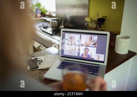 POV Senior women friends video conferencing on laptop screen in kitchen Stock Photo