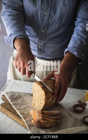 Man slicing fresh home baked sourdough bread loaf