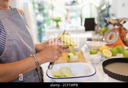 Close up woman slicing green apples for pie in kitchen Stock Photo
