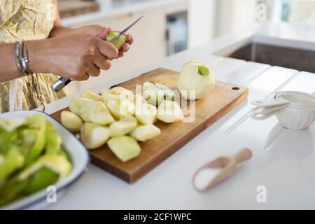 Woman slicing green apples for baking in kitchen Stock Photo
