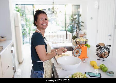 Portrait happy woman slicing apples for baking in kitchen Stock Photo