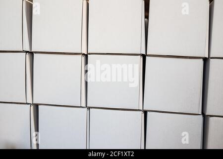 Side view of white paper boxes in rows, minimalistic design objects. Wall with cardboard square shaped empty packages in delivery room, closeup view, Stock Photo