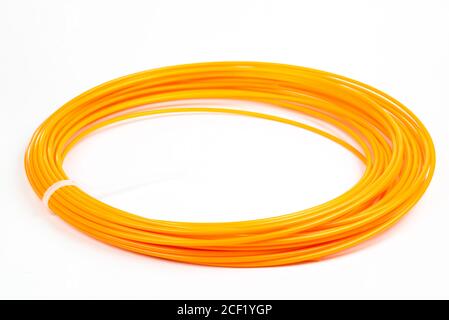Top view of orange rolled filament 3D pen PLA isolated on white. Closeup of plastic bright wire for 3D printer lying indoors, white studio background. Stock Photo
