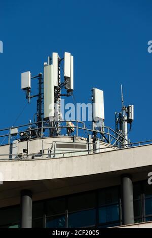 5G and 4G mobile phone antennas installed on the rooftop of a building. Blue sky Stock Photo