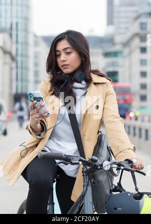 Woman on bicycle using smart phone in city Stock Photo
