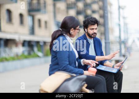 Business people with laptop working on outdoor bench Stock Photo