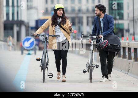 Business people talking and walking bicycles on city bridge Stock Photo