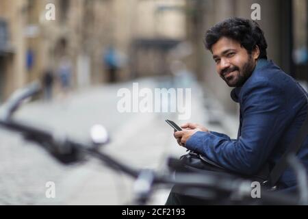 Portrait smiling businessman with smart phone on city street Stock Photo