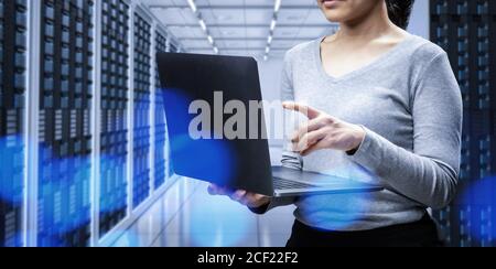 Female programmer with computer notebook in server room Stock Photo