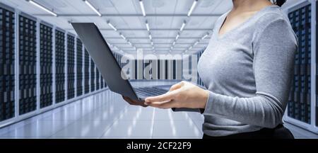 Female programmer with computer notebook in server room Stock Photo