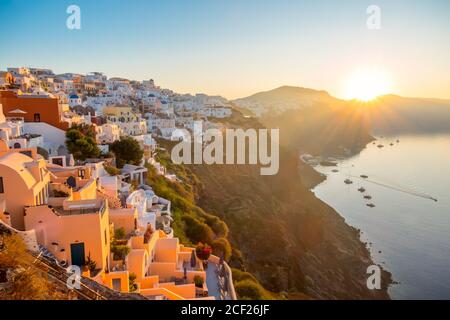 Greece. Volcanic island of Thira (Santorini). Cloudless dawn over the caldera. Many white houses of Oia city on the side of a mountain and a yacht in