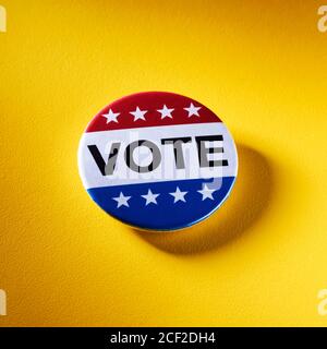 a vote badge, with the colors and the stars of the United States, on a textured yellow background Stock Photo