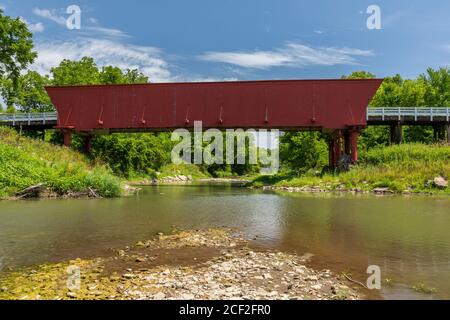 An old red covered bridge over a river. Stock Photo