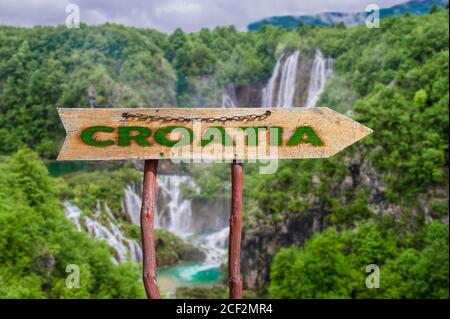 Wooden arrow road sign with word Croatia against waterfall and forest background. Travel to Croatia concept. Stock Photo