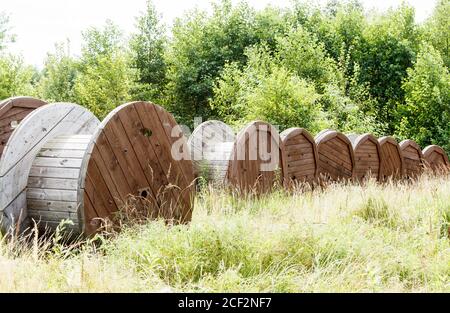several large wooden spools in the forest on sunny summer day Stock Photo