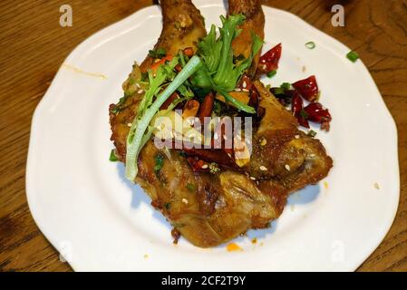 two fresh fried rabbit's legs with vegetables and peppers on the white plate Stock Photo