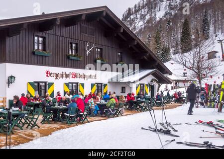 Saalbach, Austria - March 1, 2020: People skiing and eating at the ski slope restaurant, outdoor cafe with tables Stock Photo