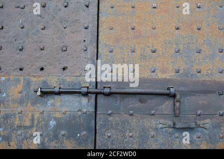 Old rusty nut bolt and iron door lock on a faded blue colored door Stock Photo
