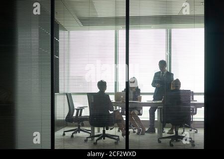 through-the-glass shot of a group of business people meeting in conference room Stock Photo