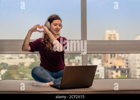 Woman making heart hands on online dating Stock Photo