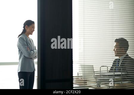 young asian businessman and businesswoman chatting talking discussing business in modern office Stock Photo