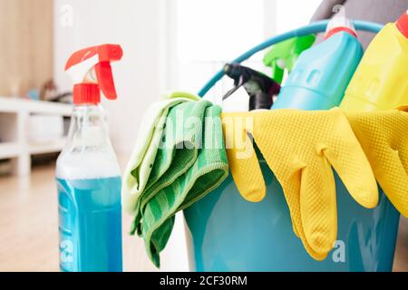 Blue bucket for cleaning with yellow gloves and a variety of detergents with rags. Room cleaning.Bucket with cleaning items on light background Stock Photo