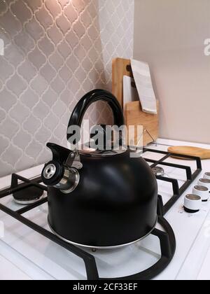 Black kettle with whistle stands on gas stove in kitchen Stock Photo