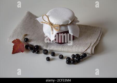 Black currant jam in glass jars. Fresh berries with leaves and stems. Autumn harvesting and preserves. Organic food. Still life photography Stock Photo