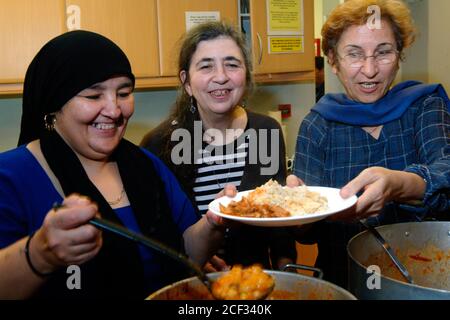 Volunteers serve curry to refugees and asylum seekers in a soup kitchen at a church hall; Bradford Yorkshire UK Stock Photo