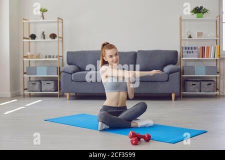 Young lady stretching arm while training at home Stock Photo