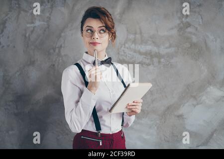 Portrait of her she nice attractive pretty creative focused wavy-haired girl writing memo planner organizer overthinking isolated on gray concrete Stock Photo