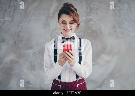 Portrait of her she nice-looking attractive lovely pretty classy focused cheerful cheery glad wavy-haired girl using digital device isolated over gray Stock Photo