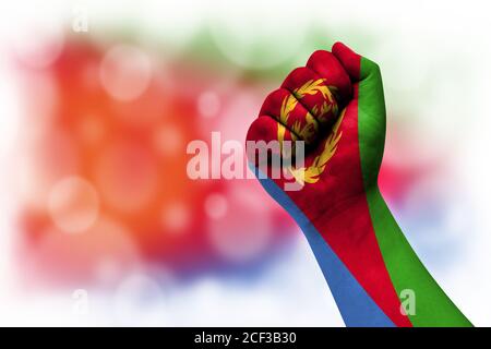 Flag of Eritrea painted on male fist, strength,power,concept of conflict. On a blurred background. Stock Photo