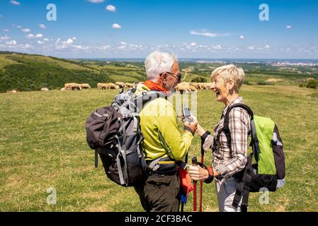 Shallow focus shot of an aged couple using an electrical compass in a big field Stock Photo
