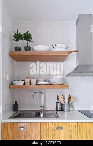 Wooden kitchen shelves with tableware on white brick tile wall in Scandinavian style Stock Photo