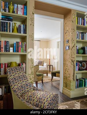 Patterned chair by recessed bookcases Stock Photo