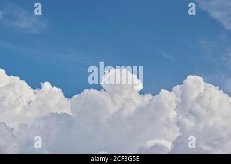 Cumulus clouds forming in the sky before the onset of a thunderstorm in a tropical climate. Separation between clouds and blue sky with copy space. Stock Photo