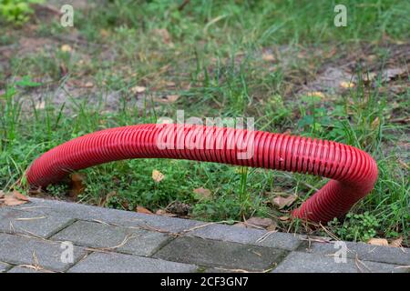 Red corrugated pipe for electric cables buried in the ground. Stock Photo