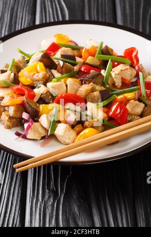 Asian stir fry chicken with eggplant, pepper and onion close-up in a plate on the table. vertical Stock Photo