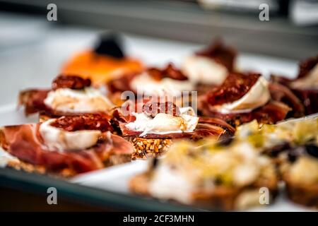 Display of store cafe shop selling Italian sandwiches with sun-dried tomatoes, mozzarella cheese on toast bread on tray counter closeup Stock Photo