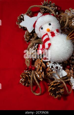red christmas background with many pine nuts and stars tied to a rope and a snow man on top Stock Photo