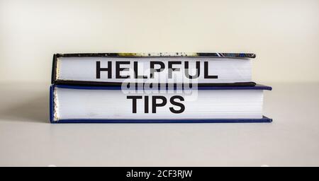 Books with text 'helpful tips' on beautiful white table. White background. Business concept. Copy space. Stock Photo