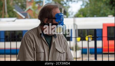 Hampshire, England, UK. 2020.  A male rail traveller wearing medical protective equipment, mask, goggles and gloves during Covid-19 outbreak. Stock Photo