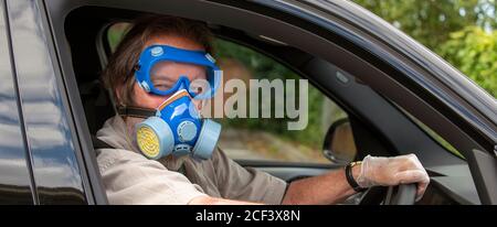 Hampshire, England, UK. 2020. Car driver wearing medical protective equipmment, mask, goggles and gloves during Covid-19 outbreak, Stock Photo