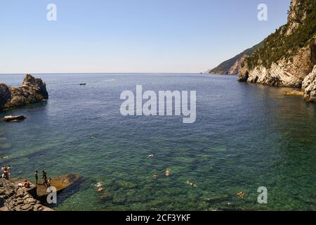 High angle view of the bay of Lord Byron with people sunbathing on the rocky shore and swimming in summer, Porto Venere, La Spezia, Liguria, Italy Stock Photo