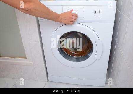 View on how a woman is turning on of the washing machine. Stock Photo