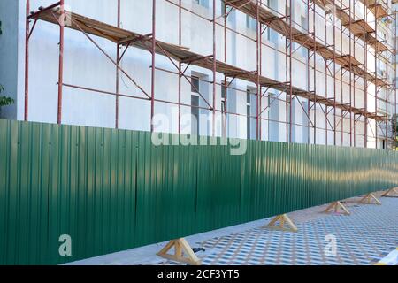 Reconstruction building with external insulation and plaster and with using of scaffolding. Temporary metal fence around the construction site Stock Photo